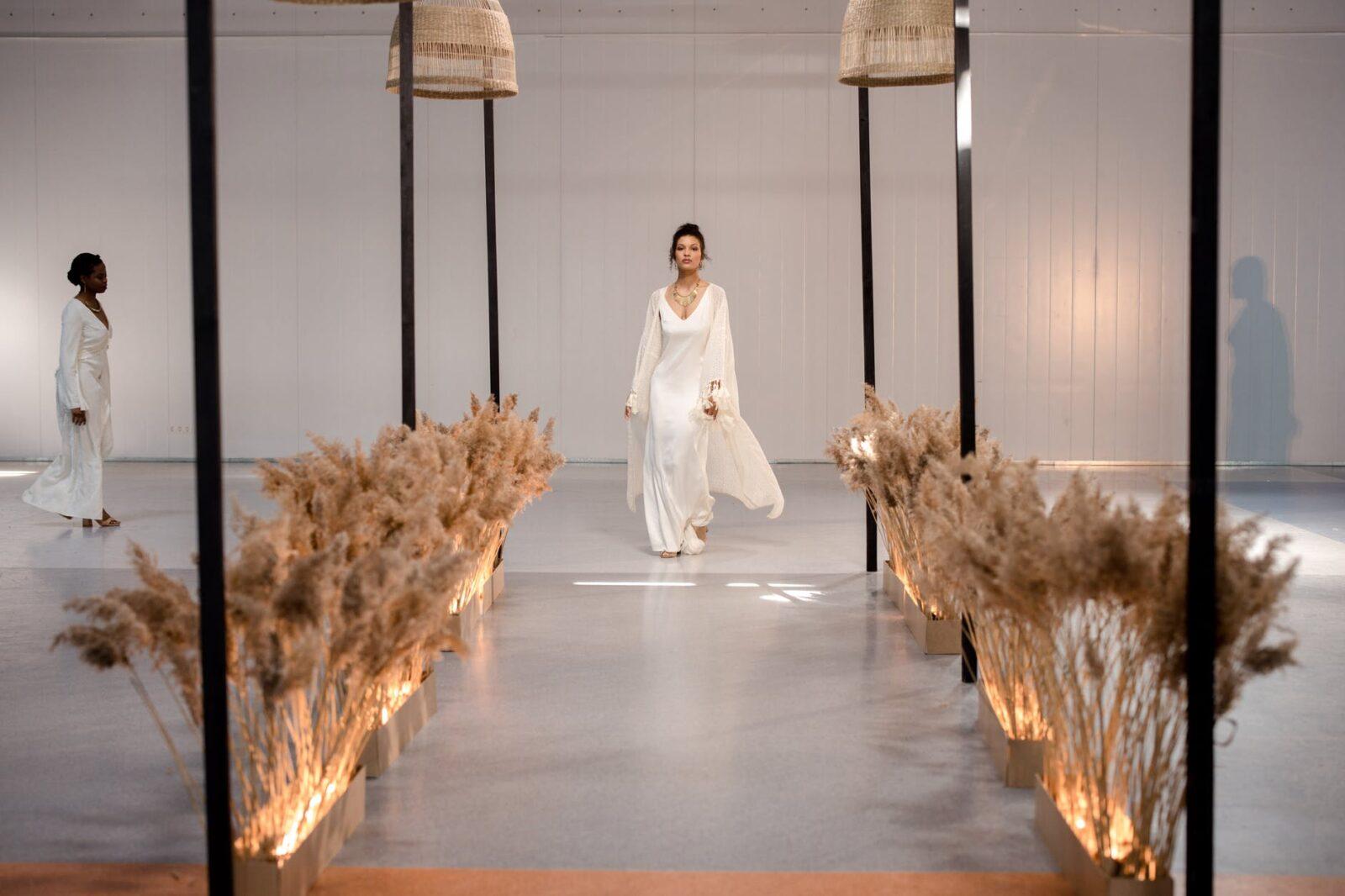 a model wearing a white dress walking on the runway