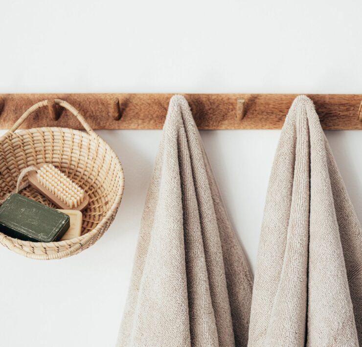 wooden hanger with towels and basket with bathroom products