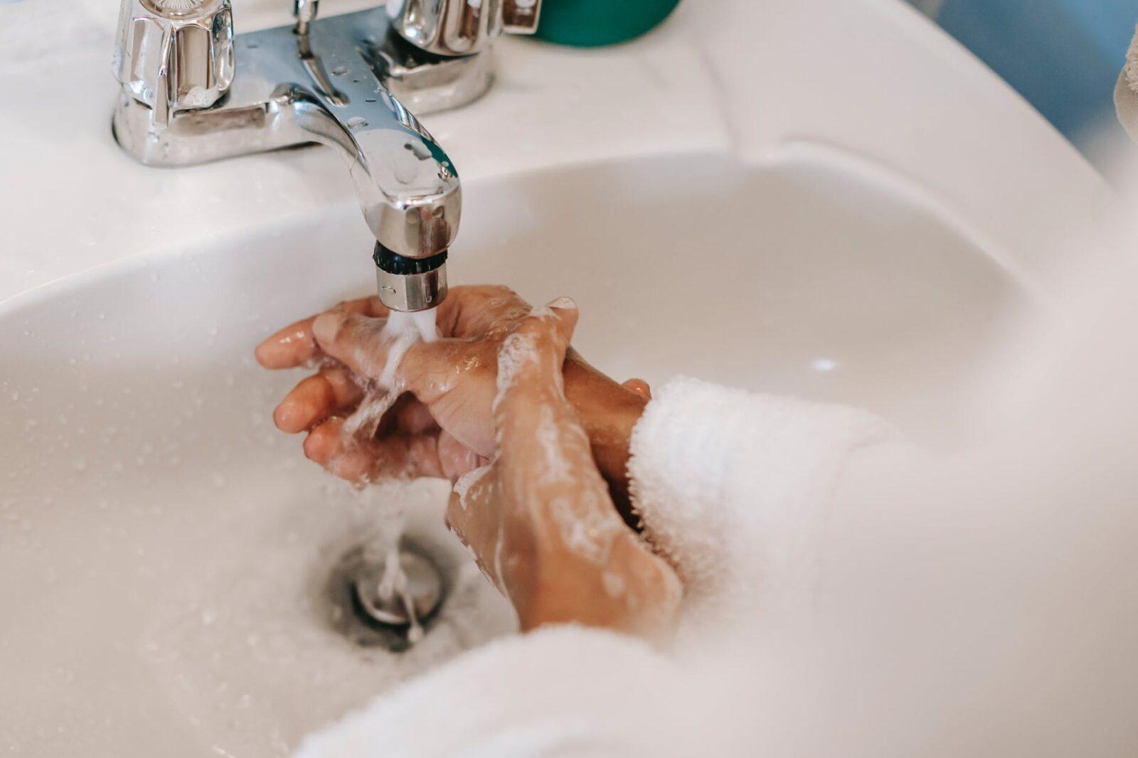 ethnic woman washing hands with soap in bathroom