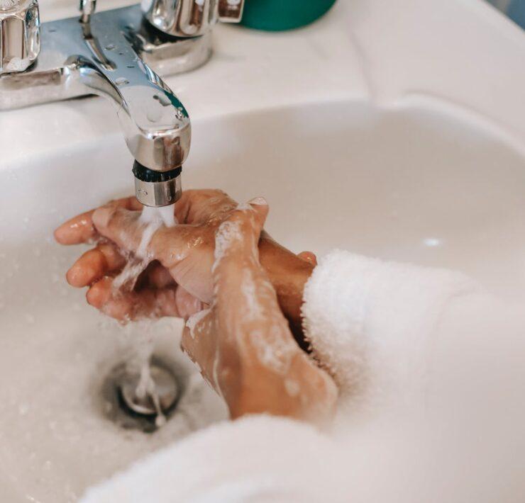 ethnic woman washing hands with soap in bathroom