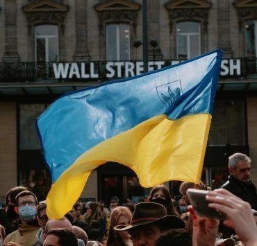 blue and yellow ukrainian flag waving above crowd of people