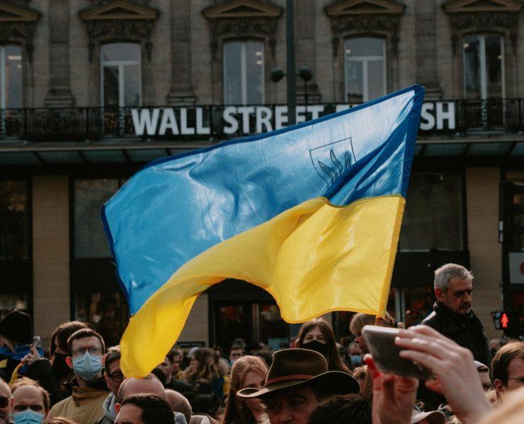 blue and yellow ukrainian flag waving above crowd of people