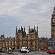 people and vehicles traveling on the road near the famous palace of westminster