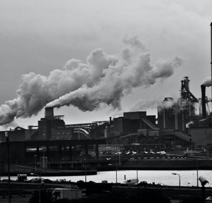 grayscale photography of locomotive train beside factory