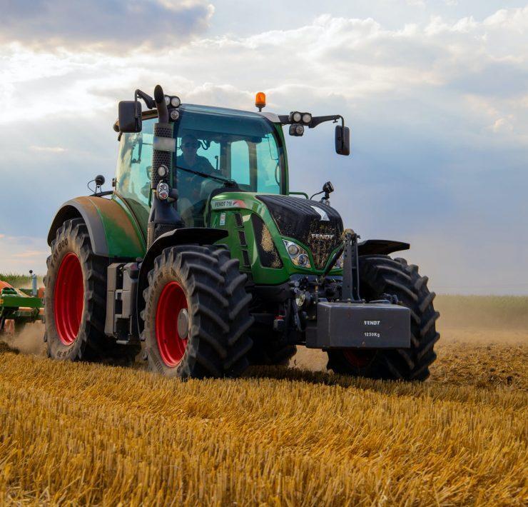 green tractor plowing the fields on focus photography