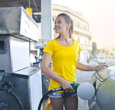 woman in yellow shirt while filling up her car with gasoline