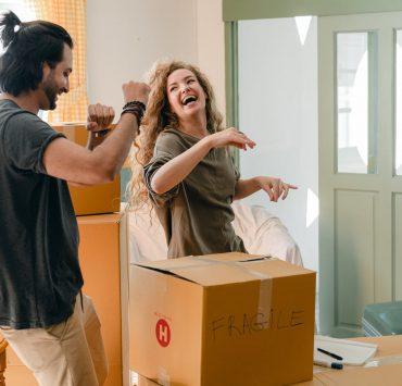 happy couple unpacking boxes and dancing