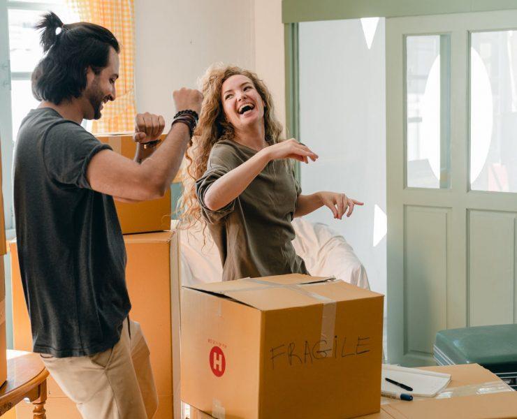 happy couple unpacking boxes and dancing