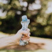 crop man crushing plastic bottle
