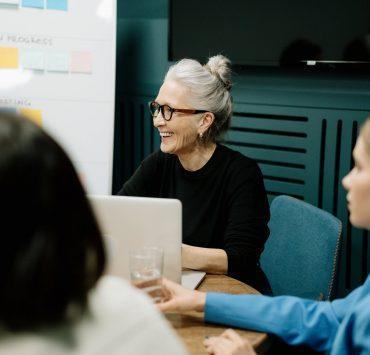 woman in black sweater and eyeglasses sitting on chair beside woman in blue shirt