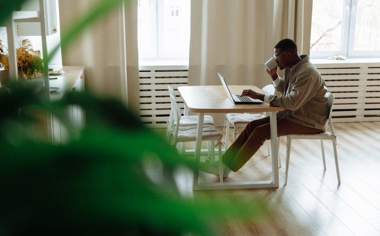 man drinking from a mug while using a laptop