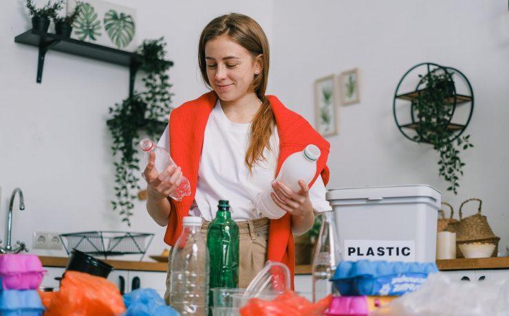 positive female sorting plastic bottles in kitchen in apartment