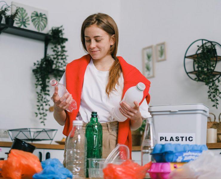 positive female sorting plastic bottles in kitchen in apartment