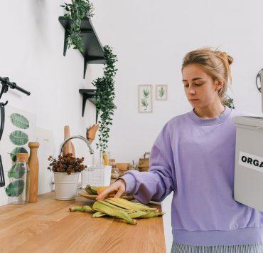 calm female sorting organic trash in kitchen in light room