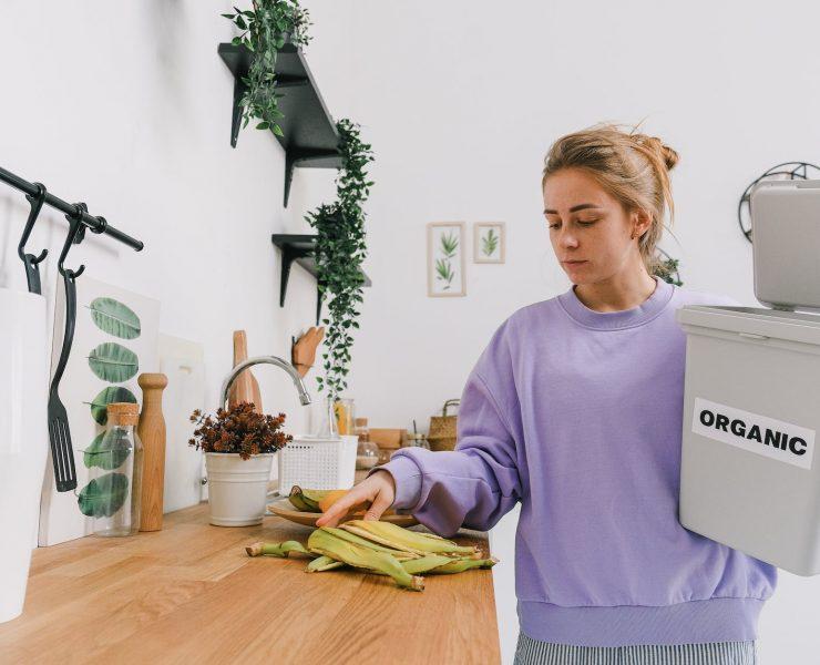 calm female sorting organic trash in kitchen in light room