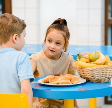girl and boy sitting around table with food