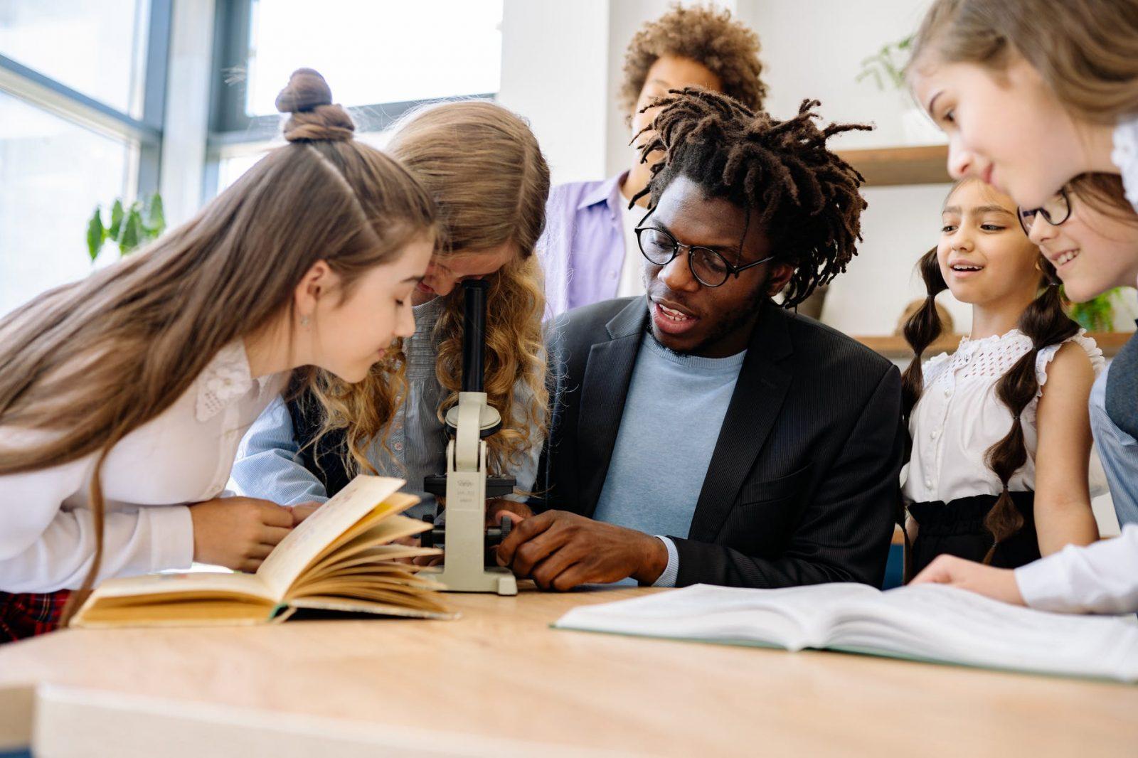 a man teaching students how to use a microscope