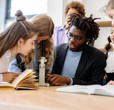 a man teaching students how to use a microscope