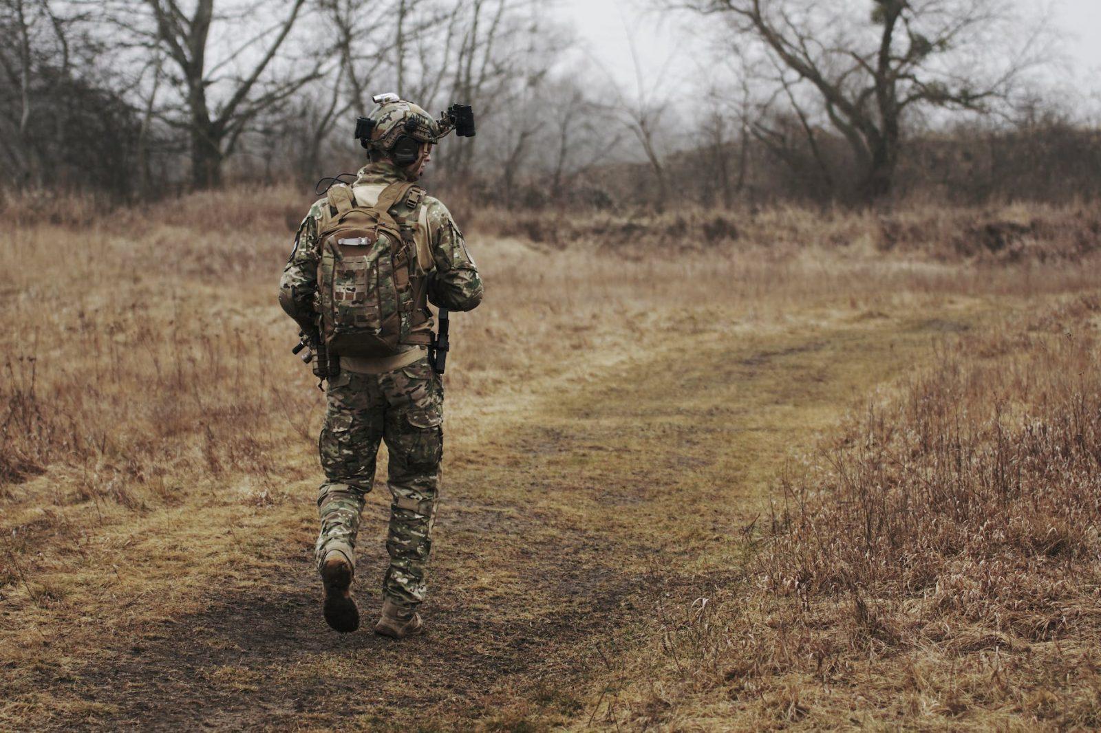 man wearing military uniform and walking through woods
