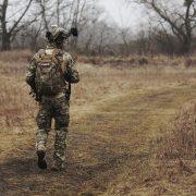 man wearing military uniform and walking through woods