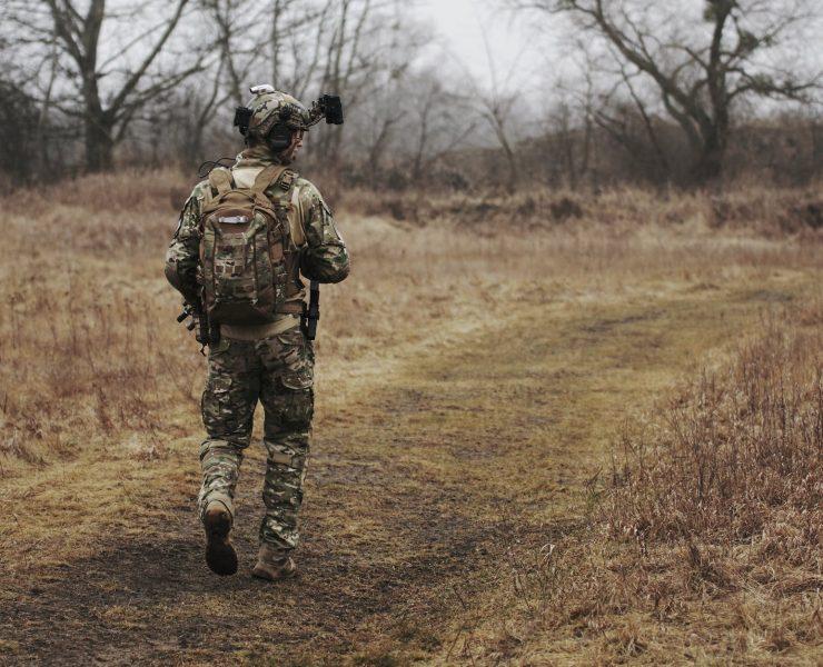 man wearing military uniform and walking through woods