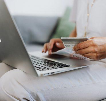 person using a macbook and holding a credit card