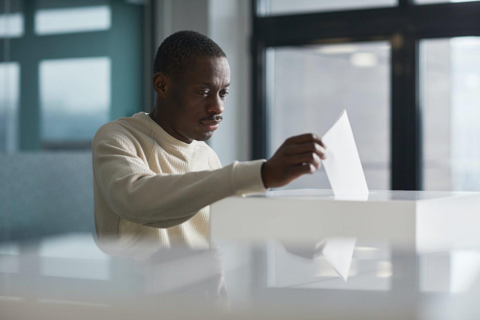 a man casting his ballot in a ballot box