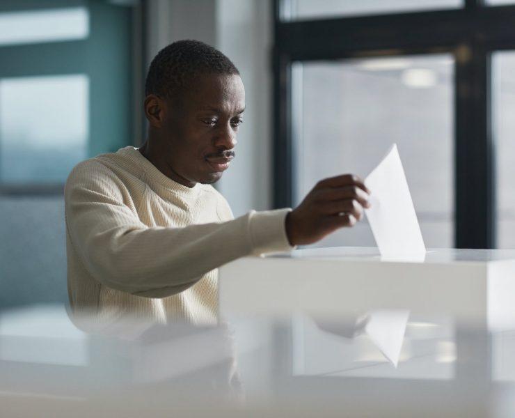 a man casting his ballot in a ballot box