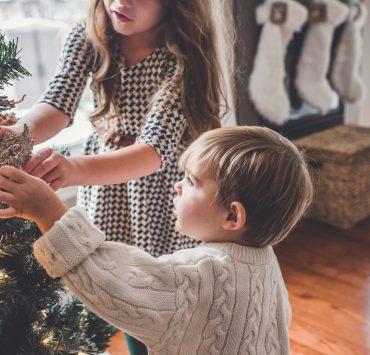boy and girl decorating Christmas tree inside room