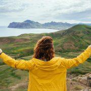 woman standing on hill in front of body of water