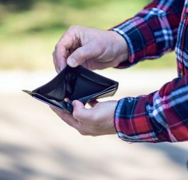 person in red blue and white plaid long sleeve shirt holding black leather bifold wallet