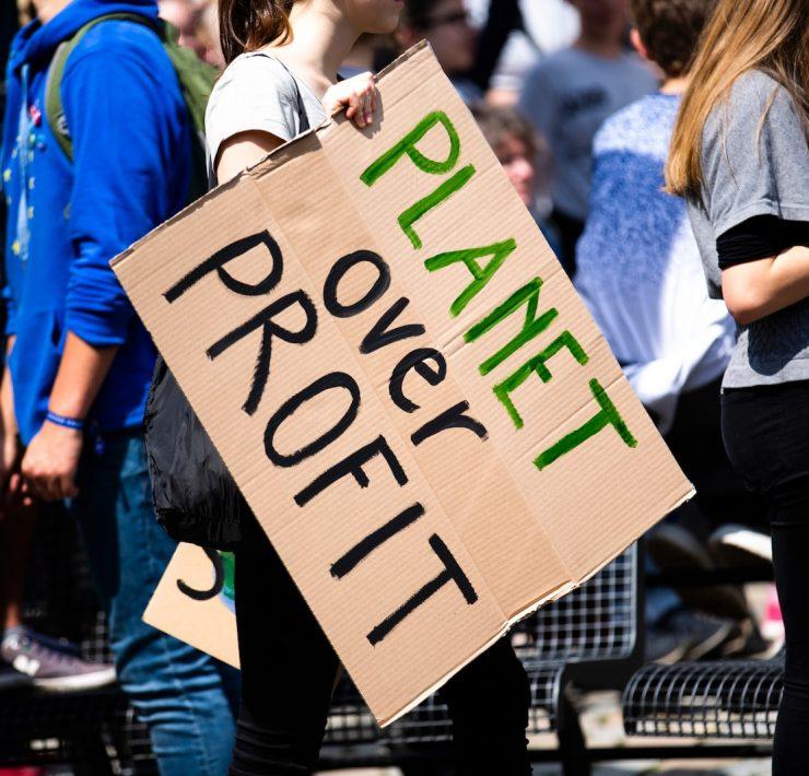 woman holding Planet over Profit placard