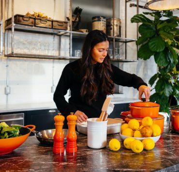 woman standing in front of fruits holding pot's lid