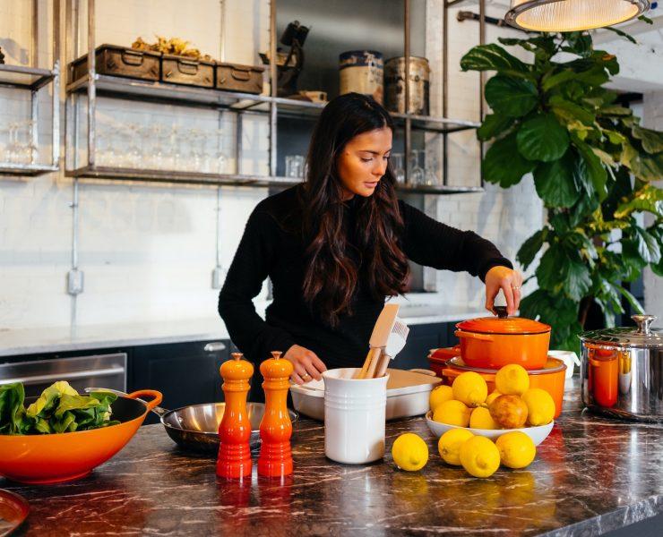 woman standing in front of fruits holding pot's lid