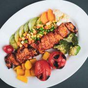 grilled meat with sliced lemon and sliced tomatoes on white ceramic plate