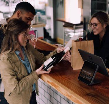 woman holding wine bottle beside man in front of woman smiling