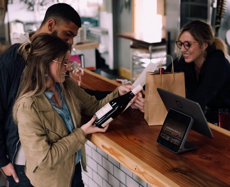woman holding wine bottle beside man in front of woman smiling