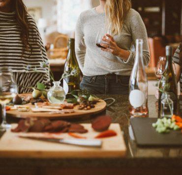two woman standing beside woman sitting in front of table