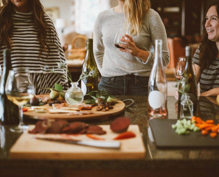 two woman standing beside woman sitting in front of table