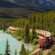 red and white train on rail near body of water during daytime