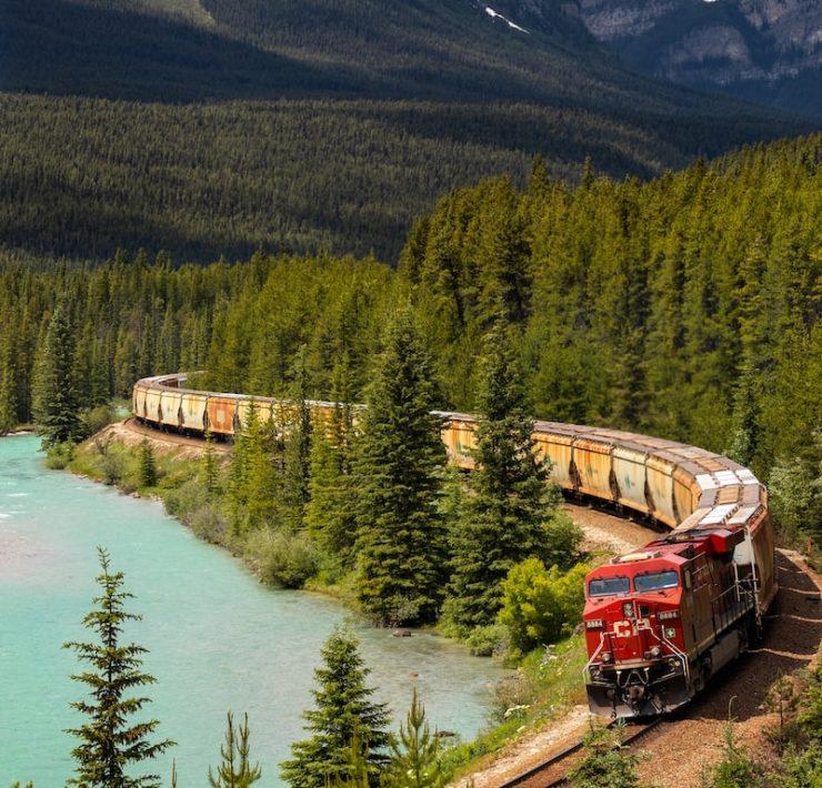 red and white train on rail near body of water during daytime