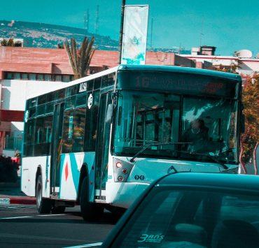 a city bus driving down a street next to a car