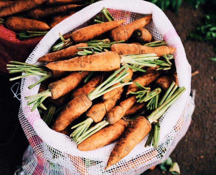ripe carrots inside white net sack