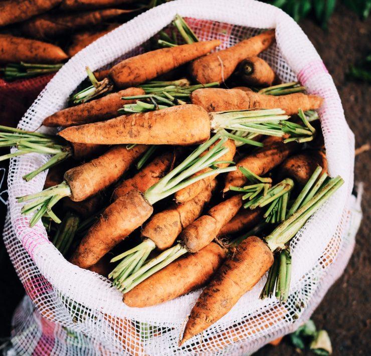 ripe carrots inside white net sack