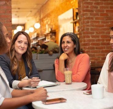 woman in black jacket sitting beside woman in white blazer