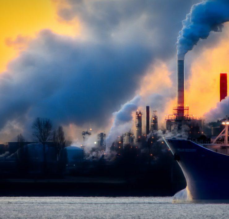 a large boat in a body of water near a factory