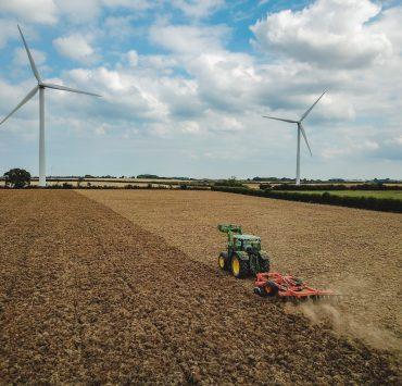 green and red tractor on brown field under blue and white cloudy sky during daytime