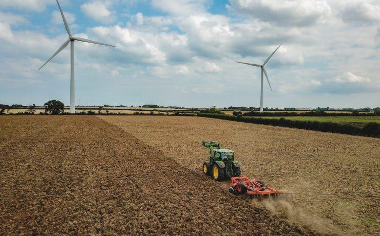 green and red tractor on brown field under blue and white cloudy sky during daytime