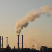 a smokestack emits from a factory in the distance