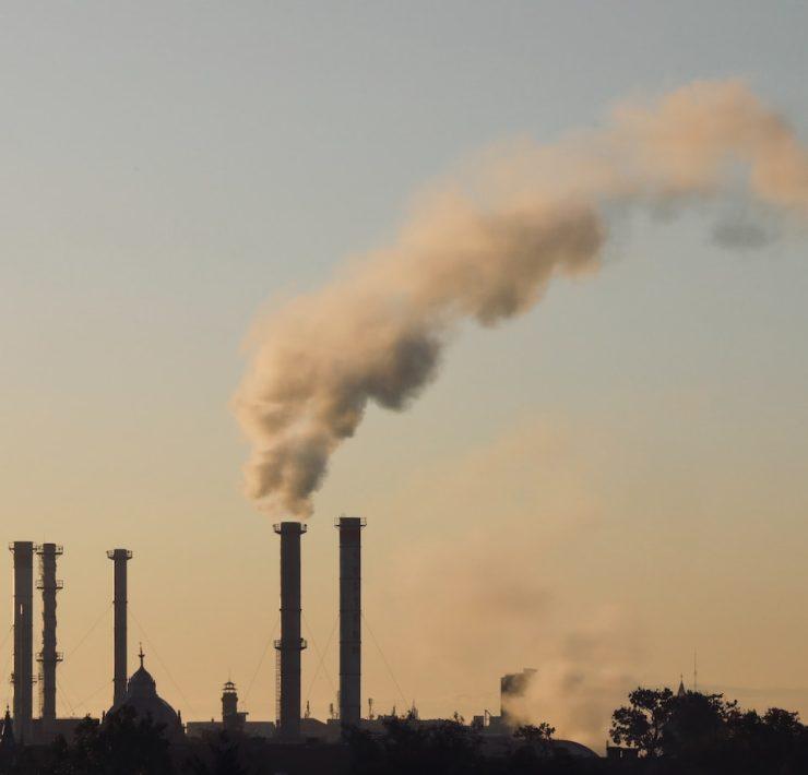 a smokestack emits from a factory in the distance